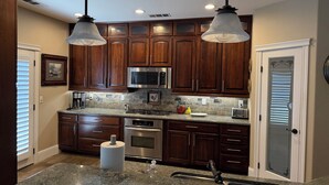 A kitchen with wooden cabinets, stainless steel appliances, granite countertops, and pendant lighting. - Home With A View, Beautiful 3 Bedroom 4 Bath, Each Bedroom with Private Bath (Redding)