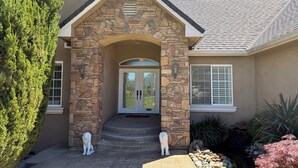 A house with a stone facade, a front door with glass panels, and two lion statues on the steps. - Home With A View, Beautiful 3 Bedroom 4 Bath, Each Bedroom with Private Bath (Redding)
