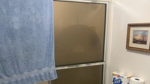 Une salle de bain avec une douche, des toilettes et un porte-serviettes.