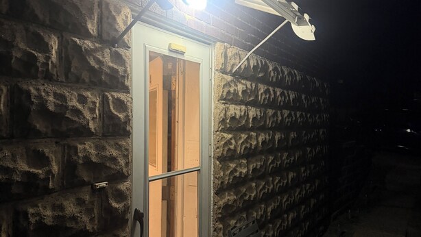 Un bâtiment en pierre avec une porte, un banc et un lampadaire.