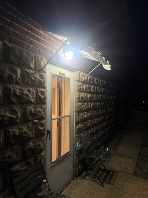 A stone building with a door, a bench, and a street lamp. - Cozy 1-bedroom apartment in Trafford with AC close to Pittsburgh for draft (Trafford)