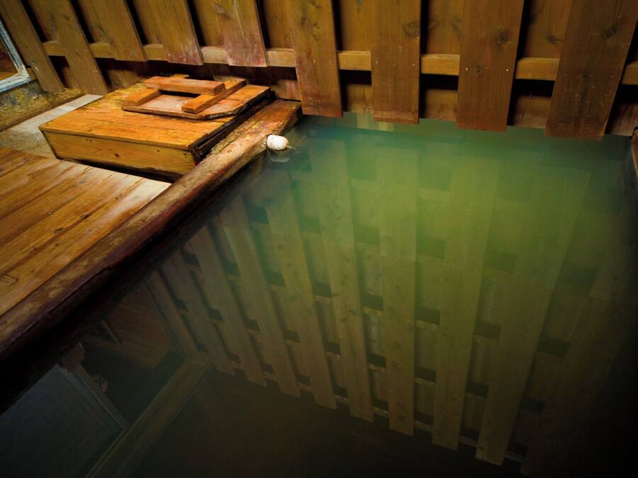 Una bañera de hidromasaje de madera con un muelle de madera y escalones que bajan hacia ella.