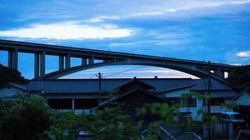 A bridge over a building with a traditional roof, surrounded by greenery.