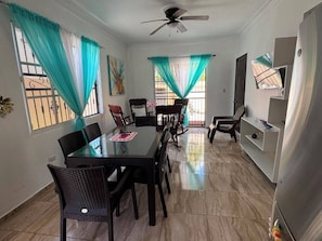 A dining area with a glass table, chairs, and a ceiling fan.