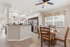 A modern kitchen with a central island, a dining area with wooden chairs, and a ceiling fan. - 2 BR Golf Course View Condo, Outdoor Pool, Discounted Golf Rounds, Dog Friendly (Branson)