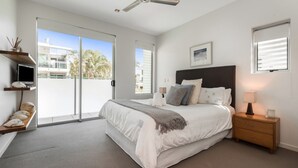 Une chambre à coucher avec un lit, des tables de chevet, un ventilateur de plafond et une fenêtre donnant sur un beau paysage.