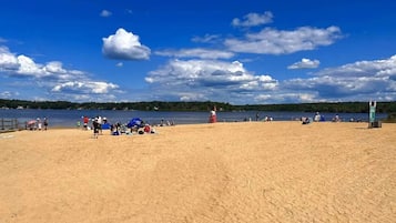 A sandy beach with people, tents, and a lifeguard tower.