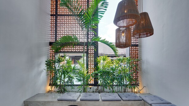 A modern interior with a seating area, a decorative wall, and hanging lights. - Rhys Apartment - Berawa (Canggu)