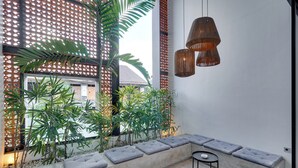 A modern interior with a seating area, a window with a view, and hanging pendant lights. - Rhys Apartment - Berawa (Canggu)