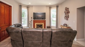 A living room with a fireplace, a leather sofa, a television, and a decorative wall piece.