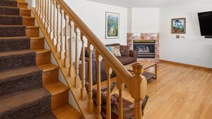 A staircase leading to a living area with a fireplace, a sofa, and a television mounted on the wall. - 3BR Home steps from Lakeside Beach and Casinos (South Lake Tahoe)