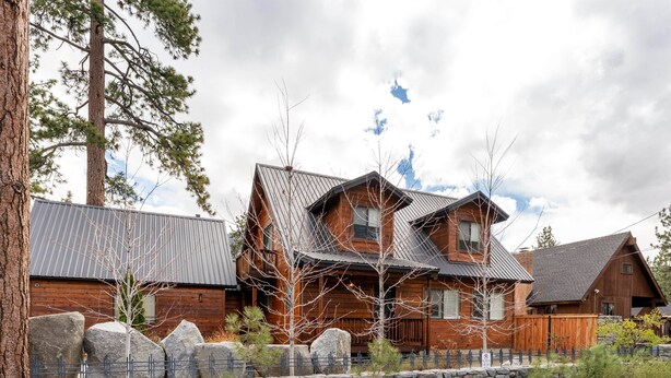 A rustic cabin with a stone wall and wooden fence, surrounded by trees and a clear sky. - 3BR Home steps from Lakeside Beach and Casinos (South Lake Tahoe)