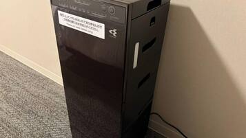 A black desktop computer with a warning label on the front, placed on a carpeted floor against a wall.