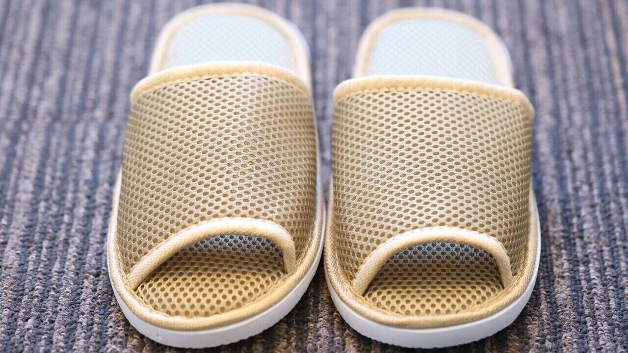 Un par de zapatillas de malla color beige con suela blanca.