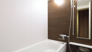 Un bagno moderno con una vasca da bagno bianca, una doccia con soffione a mano, un water e uno specchio a parete.