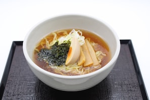 Un tazón de ramen con fideos, tofu y alga marina en caldo.
