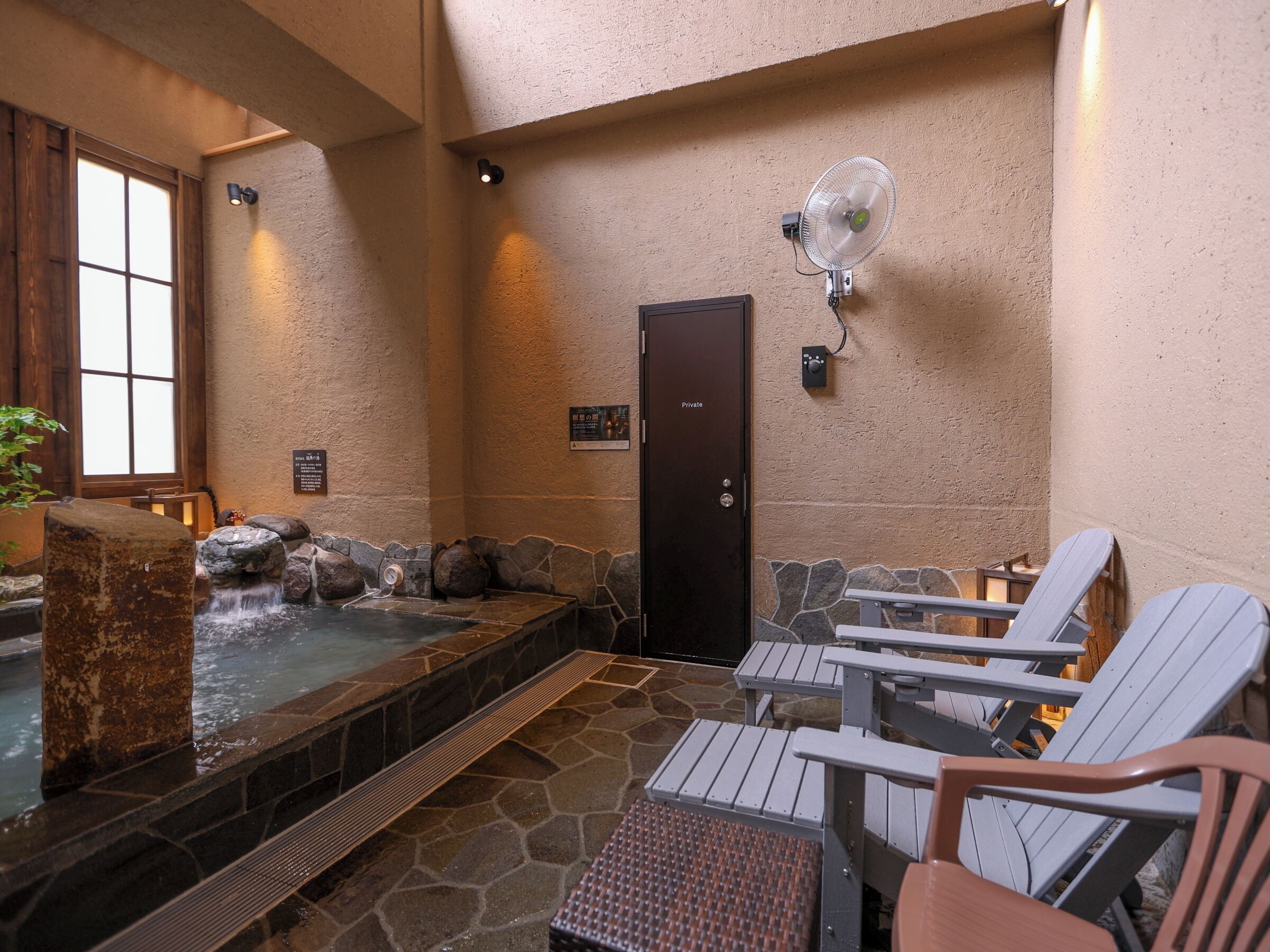 A spa area with a hot tub, stone walls, and Adirondack chairs.