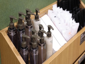 Un expositor de madera con varias botellas de productos limpiadores líquidos y toallas de papel blancas.