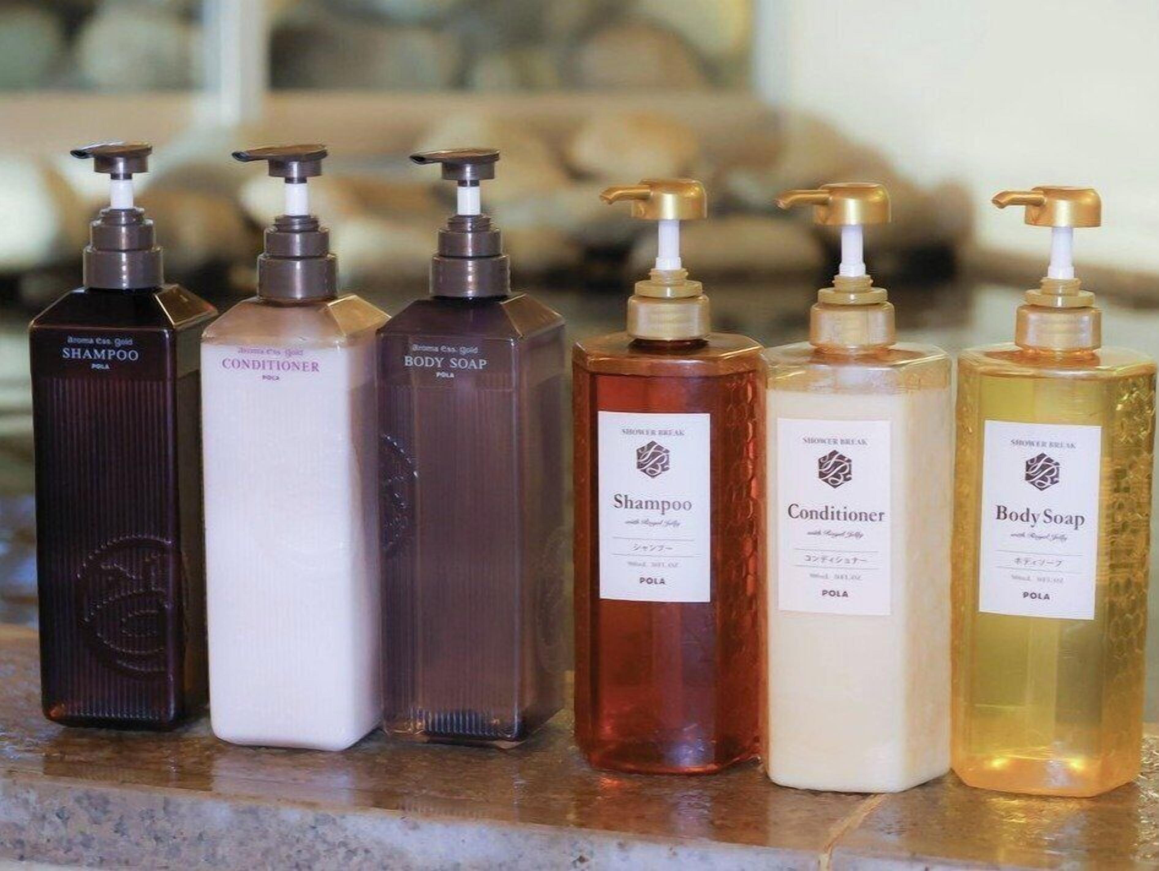 Six bottles of shampoo, conditioner, and body soap on a countertop.