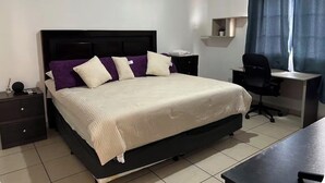 Un dormitori ben organitzat amb un llit, una taula d'estudi, una cadira i una tauleta de nit.