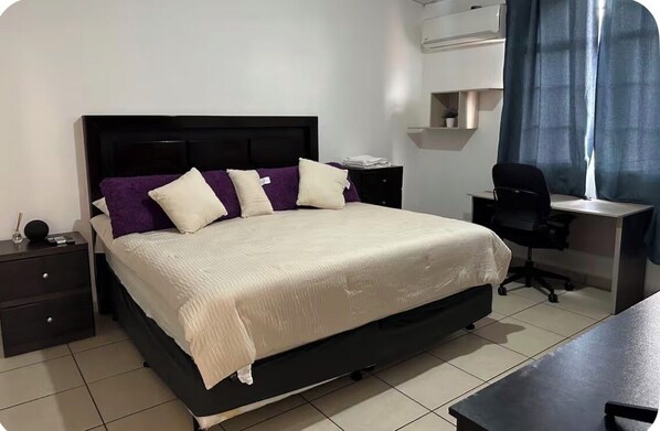 A neatly arranged bedroom with a bed, a desk, a chair, and a nightstand.