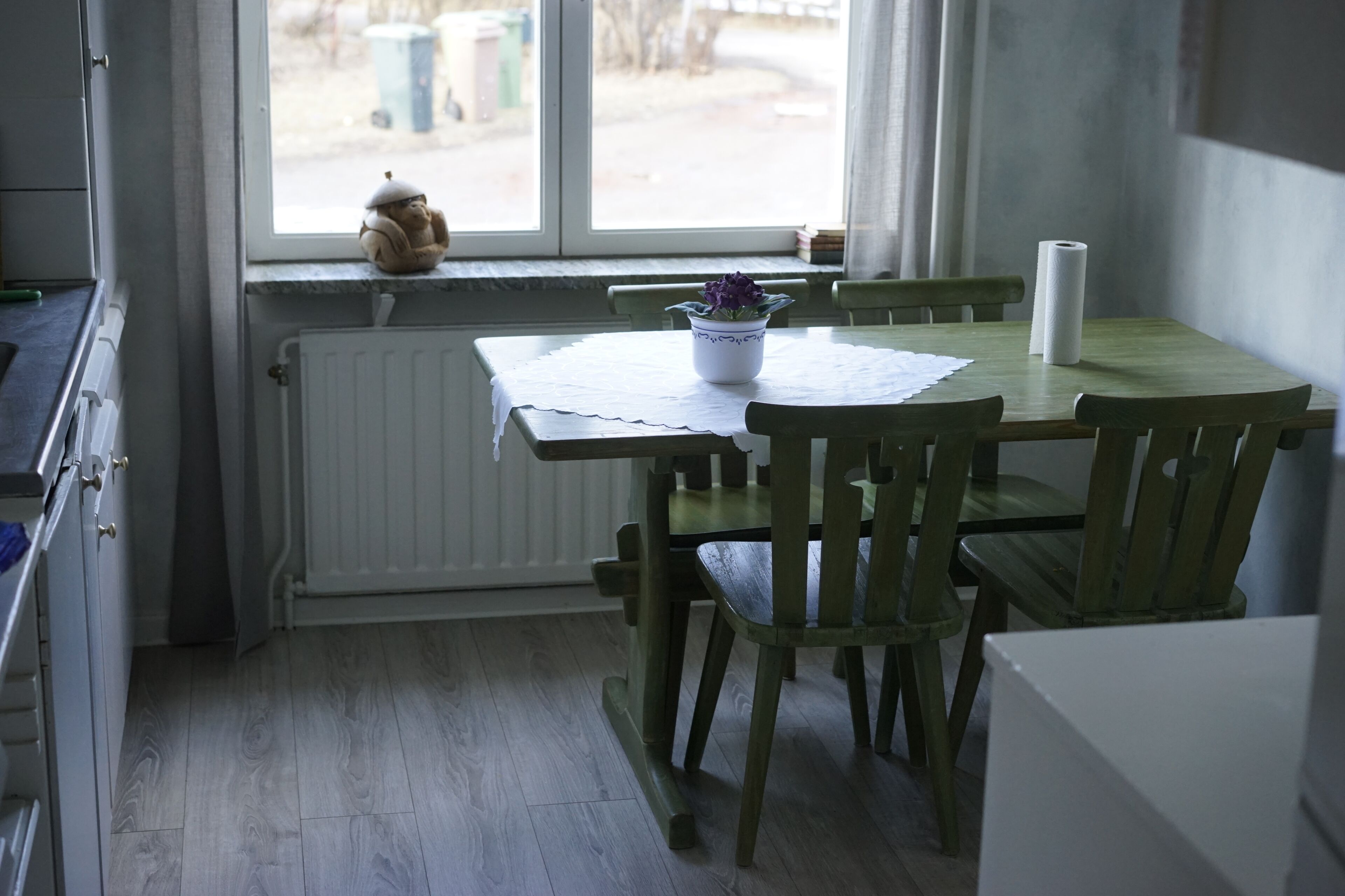 A dining area with a table and chairs, a window with a view, and a radiator.