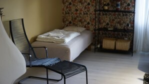 Ein Zimmer mit einem Bett, einem Sessel, einem Regal mit Dekoration und einer Wand mit Muster.