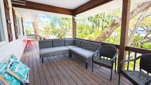 Un espacio al aire libre cubierto con un sofá de mimbre, dos sillones y una mesa roja.