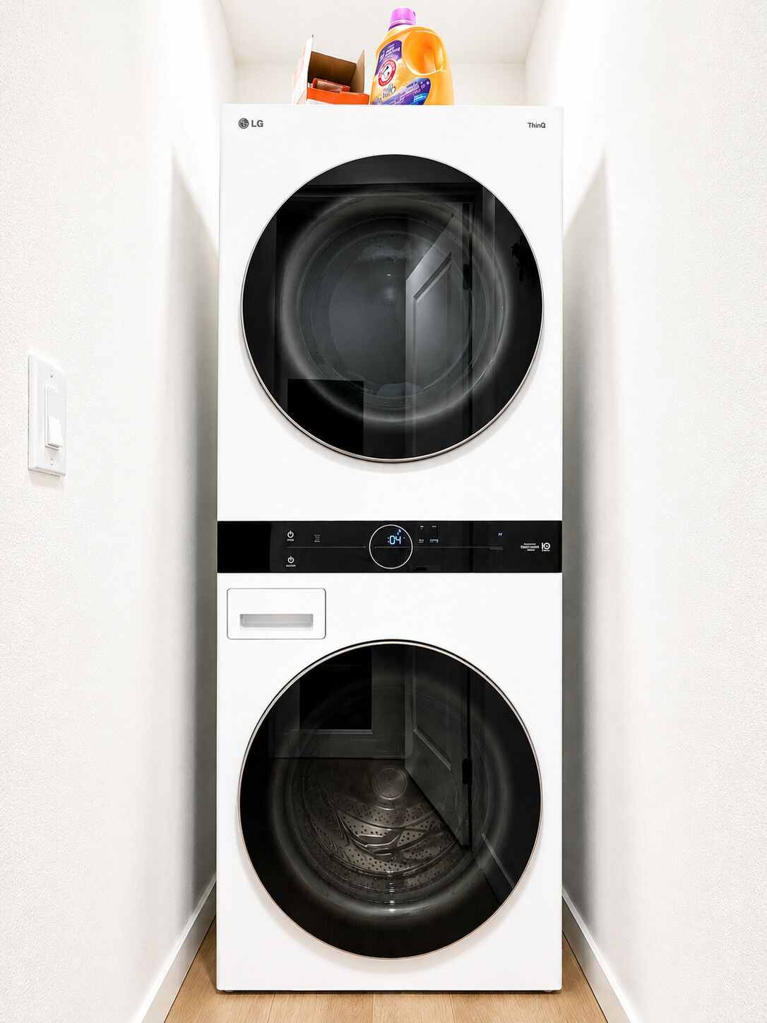 Vista frontal de uma máquina de lavar de portas duplas, com painel de controle e uma embalagem de detergente no topo.