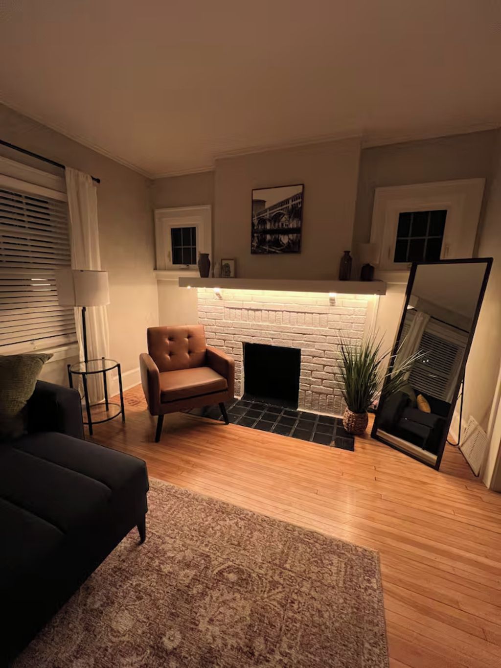 A living room with a fireplace, a sofa, a chair, and a rug.