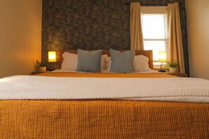 A hotel room with a large bed, two bedside tables, a window with curtains, and a patterned wall. - Boutique Cleveland Vibe - Neon Moss Wall - King Bed - Queen Bed (Lakewood)