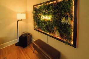 Ein Zimmer mit einer Wandpflanzenwand, einer Bank und einer Stehlampe.