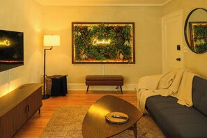 Ein Wohnzimmer mit Fernseher, Couch, einer Holz-Kaffeetisch, einer Bank und einem Wandbild mit dem Wort 'Cleveland'.