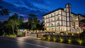 A multi-story hotel with a restaurant and bar on the ground floor, a covered entrance, and a parking area. - Osho Hotel, Restaurant & Banquet (Palampur)