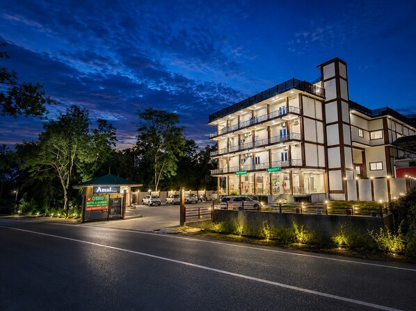 Un hotel de varios pisos con restaurante y bar en la planta baja, entrada cubierta y zona de estacionamiento.