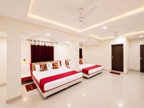 A modern hotel room with two beds, a ceiling fan, and a door.