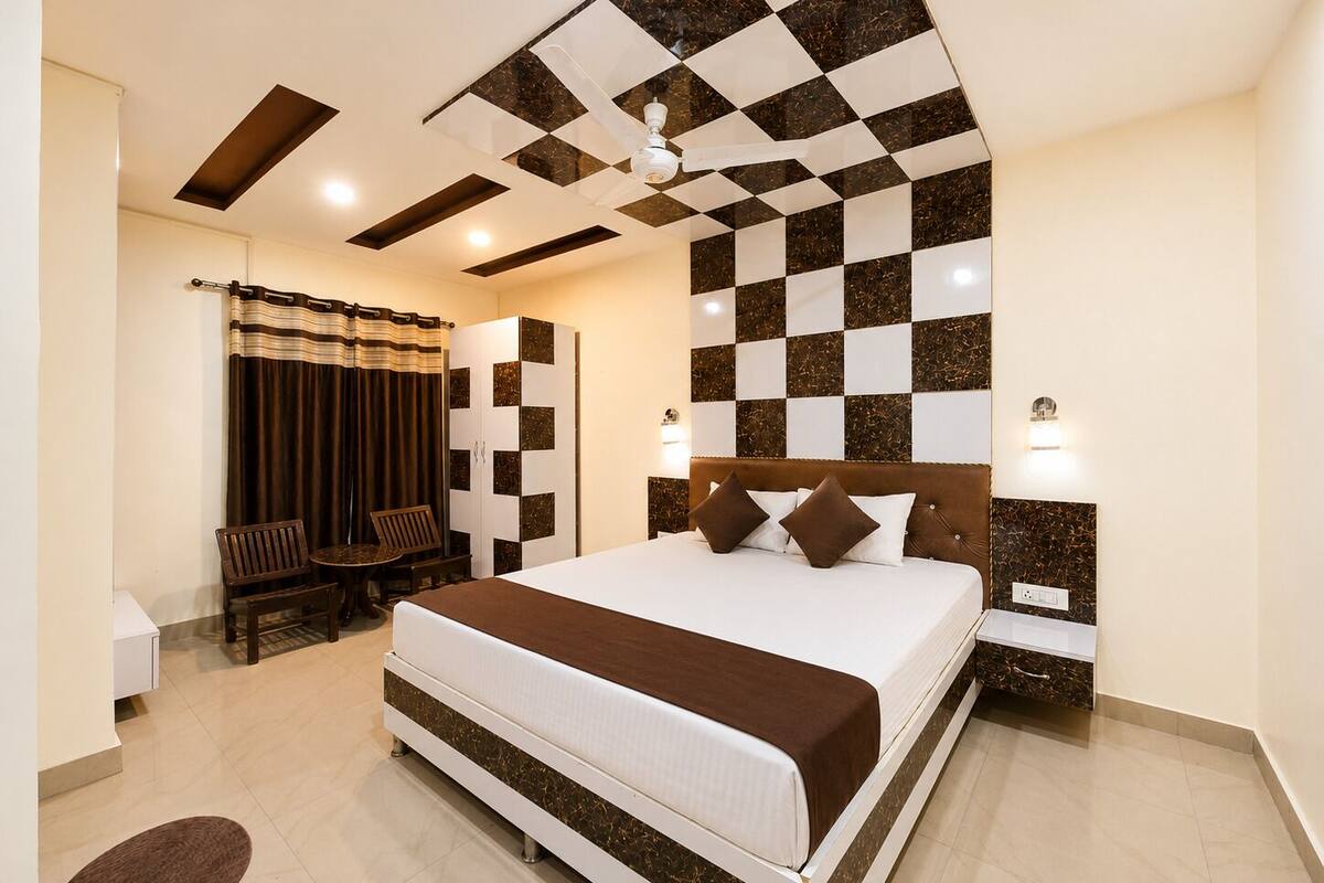A hotel room with a large bed, a ceiling fan, a desk with a chair, and a wardrobe.
