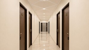 A hotel hallway with doors numbered 301 and 302, a tiled floor, and recessed ceiling lighting. - Osho Hotel, Restaurant & Banquet (Palampur)