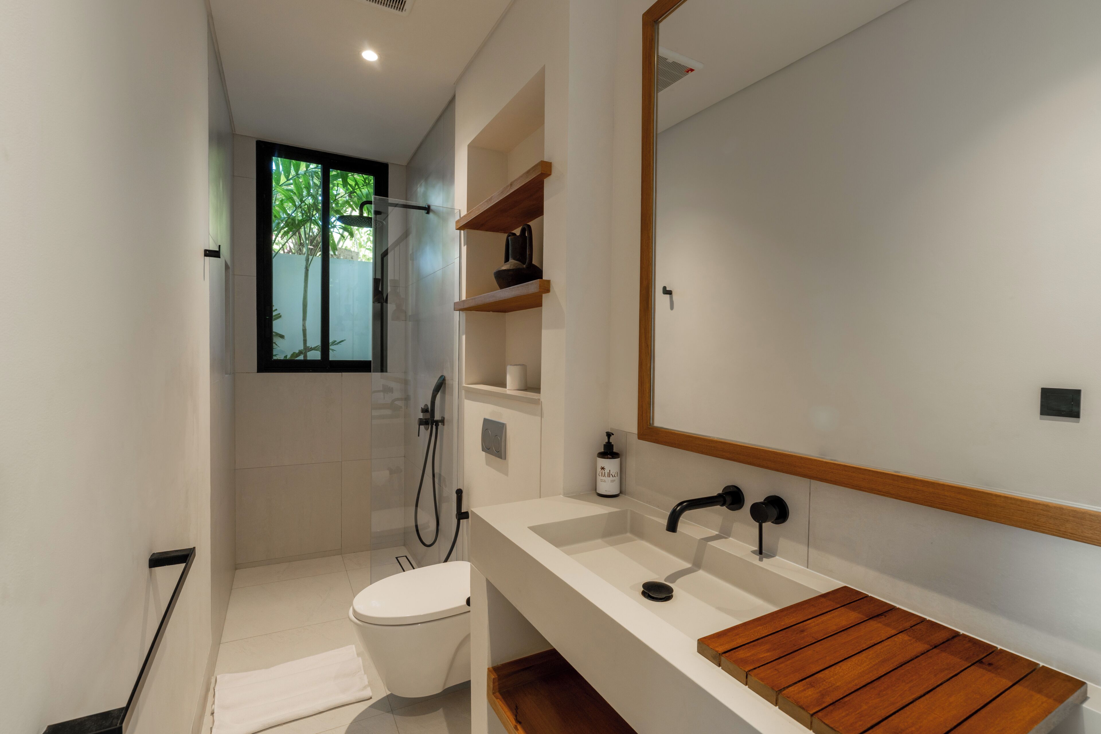 Een moderne badkamer met een witte wastafel, een houten wastafelmeubel en een grote spiegel.