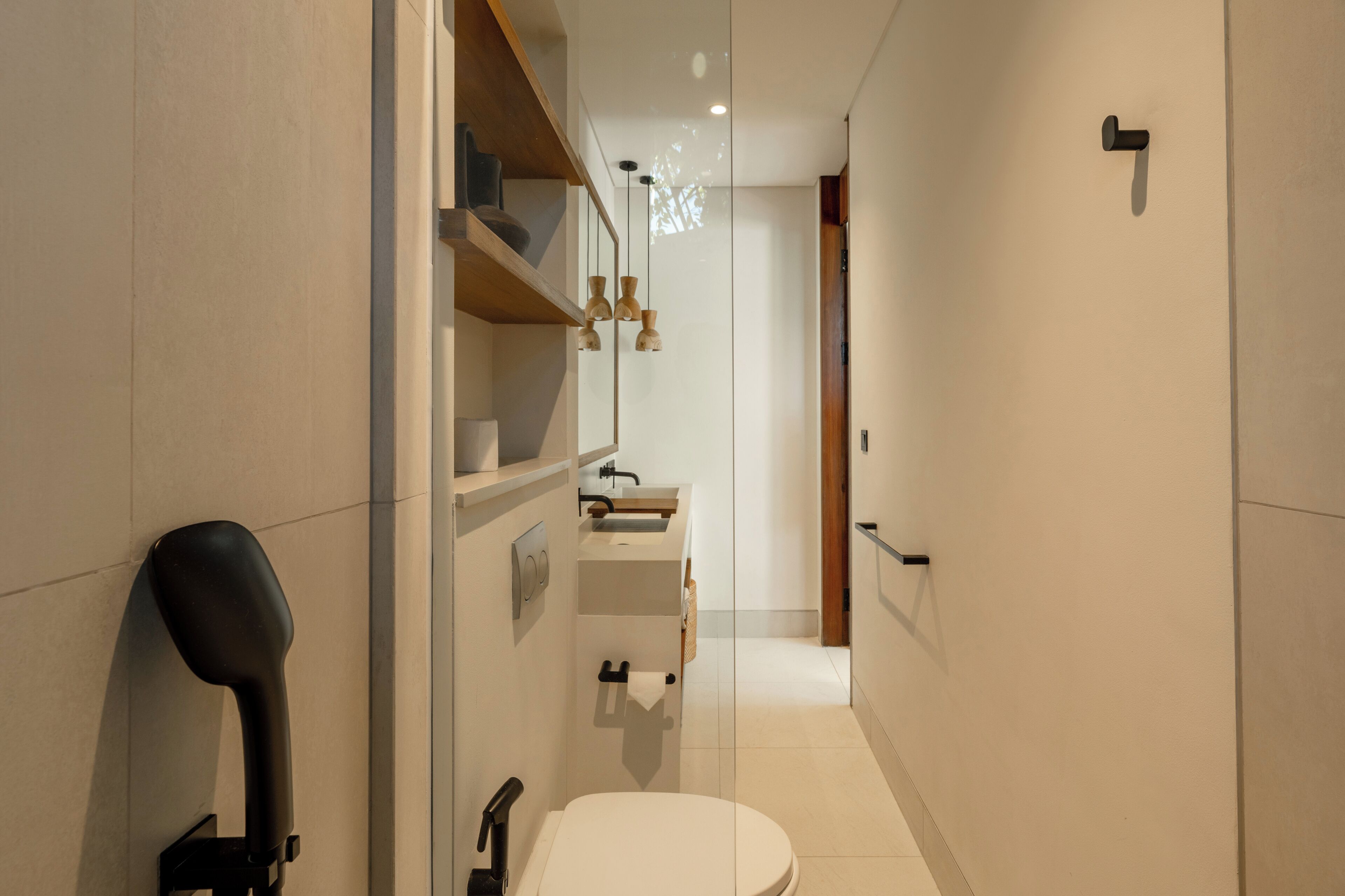 A modern bathroom with a toilet, sink, and shelves.