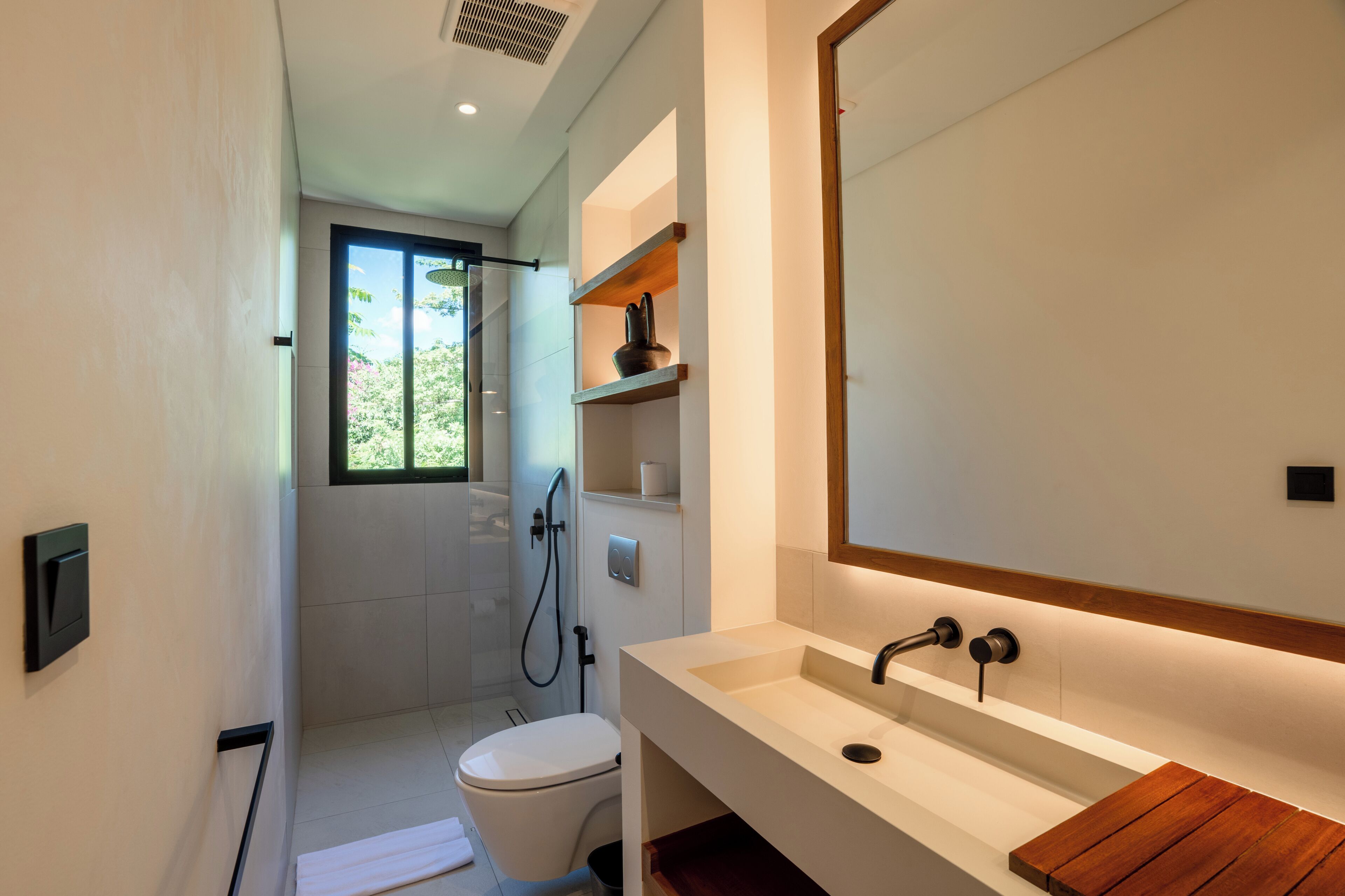 Een moderne badkamer met toilet, douche en wastafel.