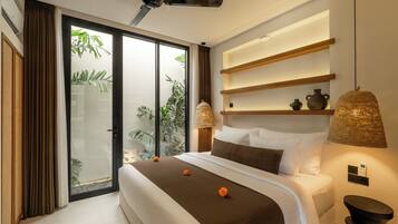 Een moderne hotelkamer met een groot bed, een plafondventilator, een schuifdeur naar een balkon en een wandplank met decoratieve objecten.