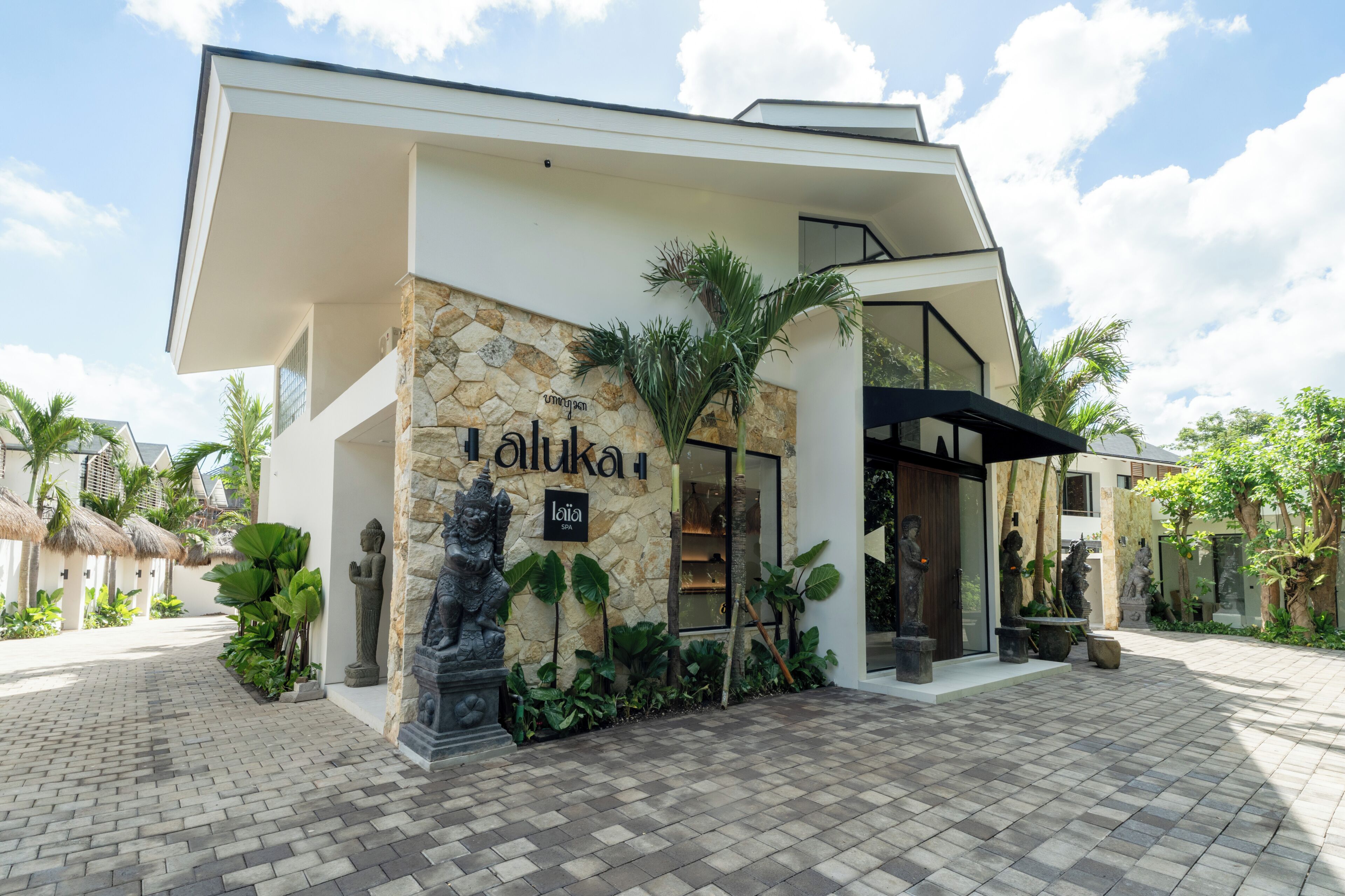 A modern building with a stone facade, a sign reading 'Lala,' and tropical plants.