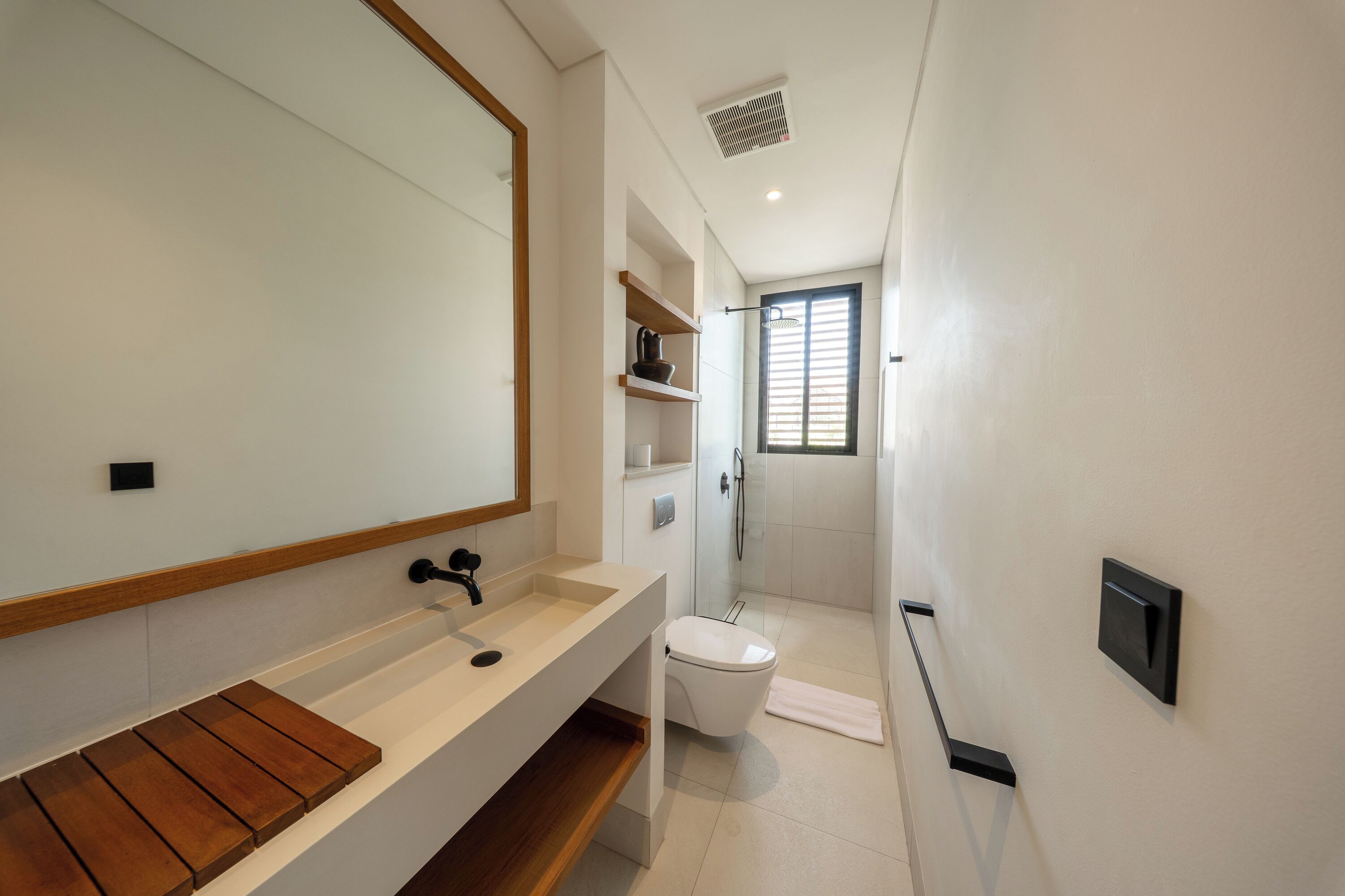 A modern bathroom with a large mirror, a sink, a toilet, and a shower area.