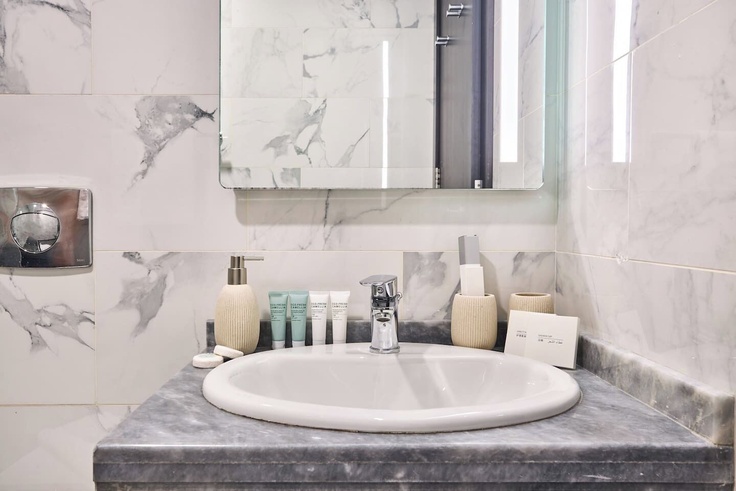 A bathroom with a marble sink, a mirror, and toiletries.