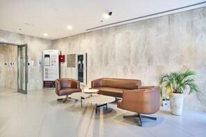 A modern lobby with a marble wall, a reception desk, and leather seating. - Modern & Spacious 2-Bedroom Apartment in Dubai South (Dubai)