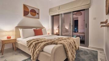A bedroom with a large bed, a nightstand, a lamp, a window with a view, and a painting on the wall.