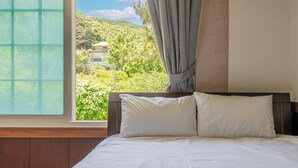 A bedroom with a bed, a window with curtains, and a view of greenery and a building outside. - Ganghwado Gagopa Family Group Pension (Incheon)