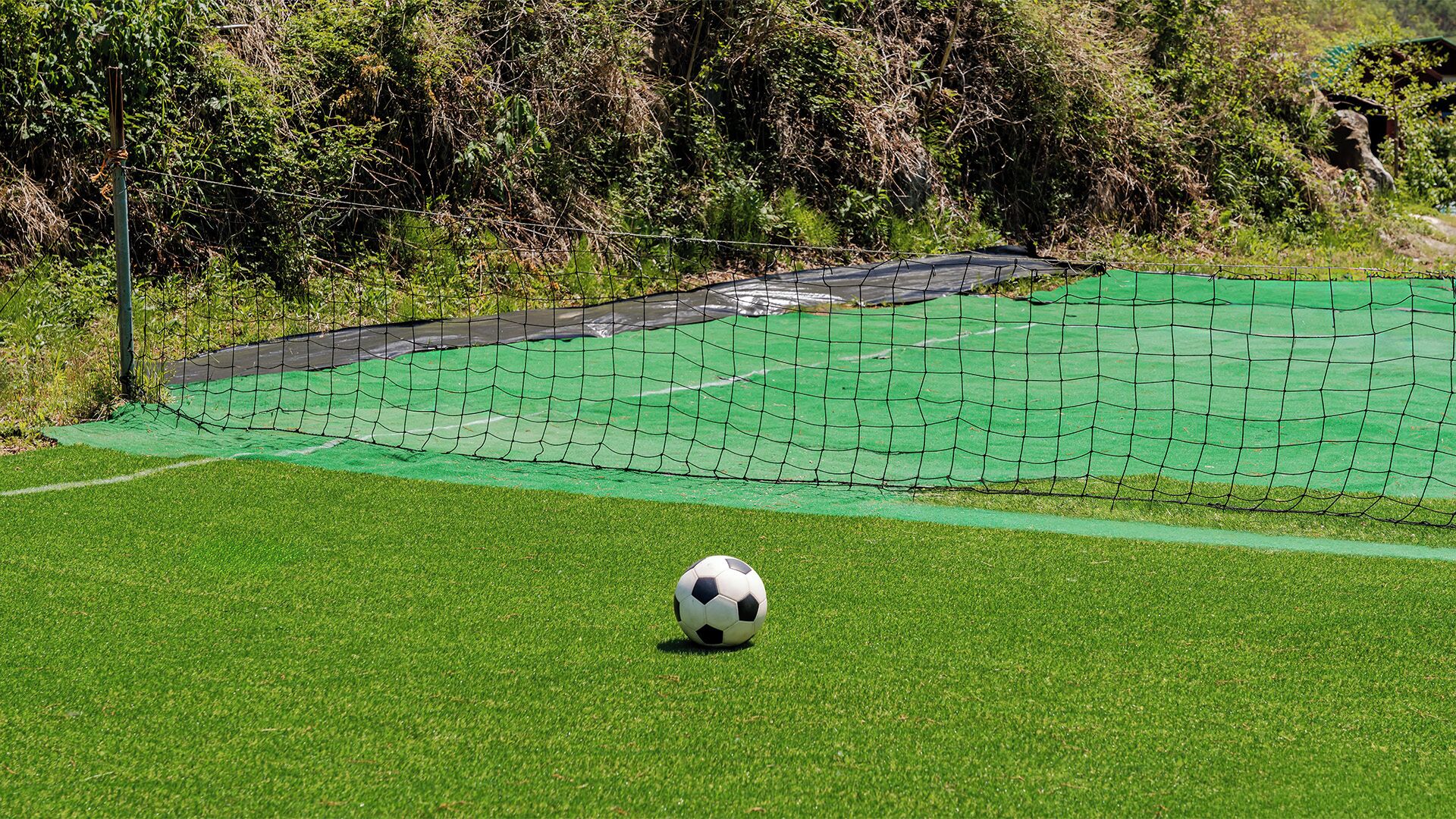 Un terrain de football avec des poteaux de but et un ballon de football au premier plan.