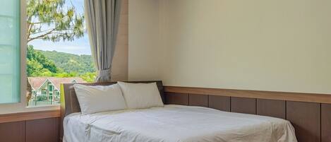 A bedroom with a bed, a window with curtains, and a view of greenery outside.